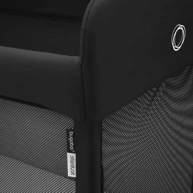 Close-up of the sleek finishes of the Bugaboo Stardust portacot in black colourway. The Bugaboo logo and product tag are visible.